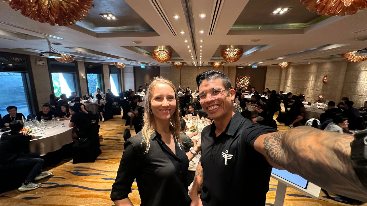 Luke and Candice taking a selfie with a ballroom of corporate participants