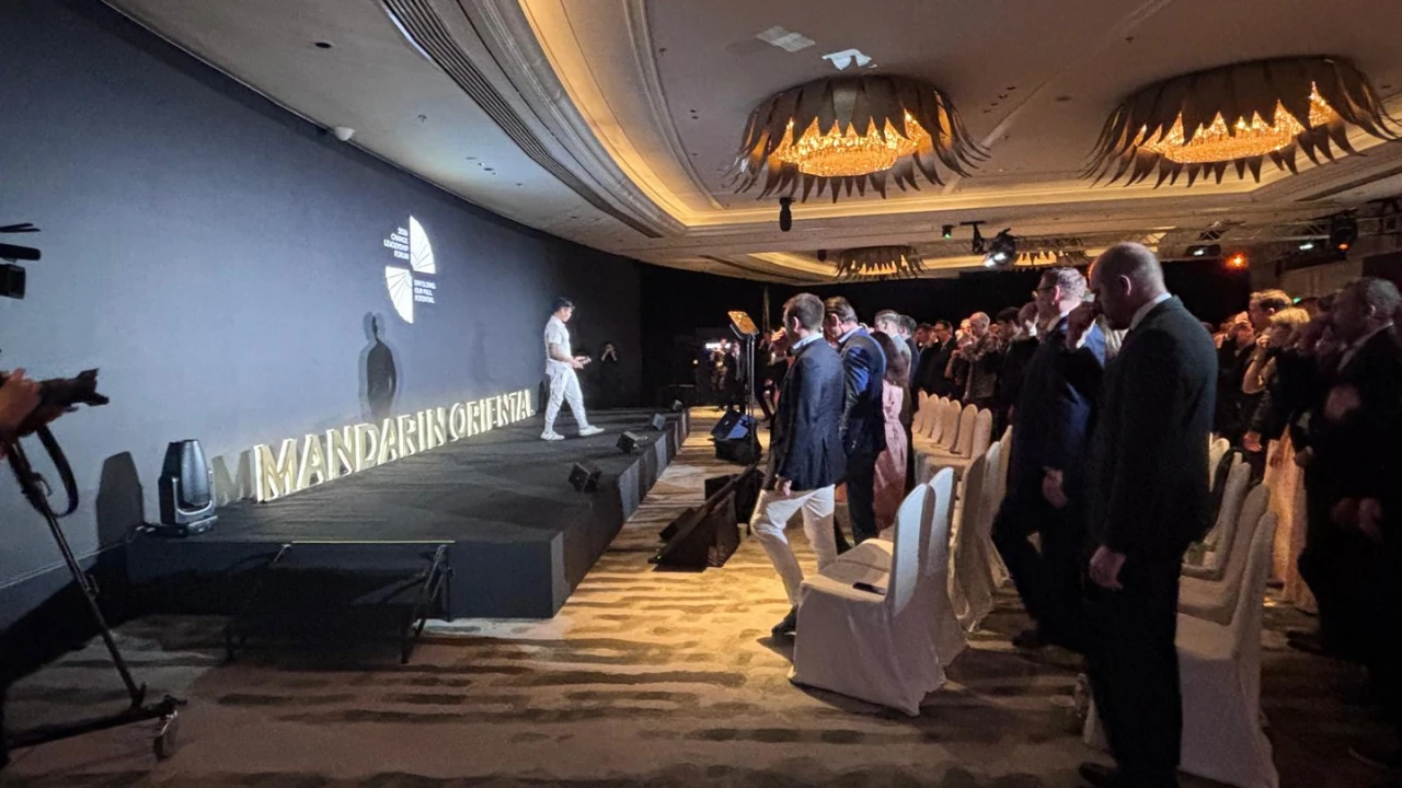 Luke leading a standing audience through a breathing exercise on stage at Mandarin Oriental
